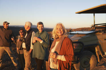 Porträt glückliche ältere Frau auf Safari trinkt Champagner mit Freunden - CAIF23751