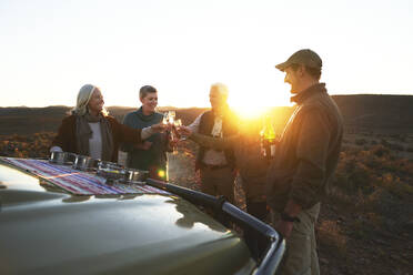 Safari-Gruppe stößt bei Sonnenuntergang mit Champagnergläsern an - CAIF23756