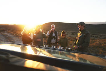 Safari-Gruppe trinkt Champagner bei Sonnenuntergang - CAIF23757