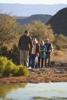 Safari-Reiseleiter führt Gruppe durch sonniges Wildschutzgebiet - CAIF23771