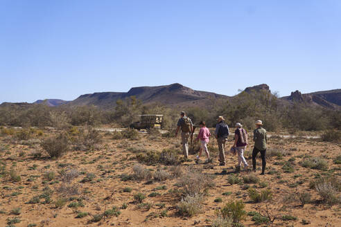 Safari-Gruppe auf dem Rückweg zum Geländewagen im sonnigen Wildschutzgebiet - CAIF23778
