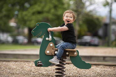 Sorglos niedlich Kleinkind Mädchen Reiten Dinosaurier Spielzeug auf dem Spielplatz - CAIF23795