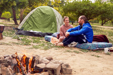 Junges Paar beim Zelten, das sich auf dem Campingplatz unterhält - CAIF23822