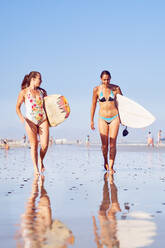 Junge Surferinnen mit Surfbrettern am sonnigen Strand - CAIF23824