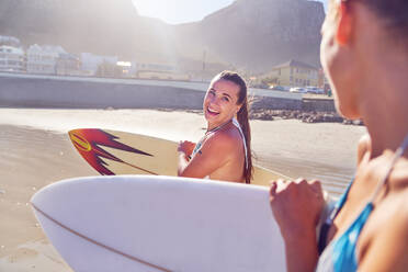 Glückliche junge Surfer-Freundinnen mit Surfbrettern am Strand - CAIF23825