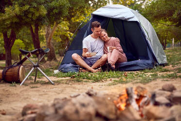 Happy affectionate couple relaxing in tent at campsite - CAIF23826