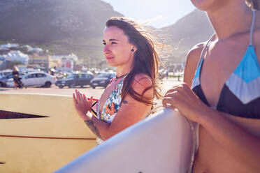 Selbstbewusste Surferin mit Surfbrett am sonnigen Strand - CAIF23832