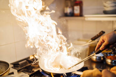 Indischer Koch flambiert Essen in Restaurantküche, Nahaufnahme - OCMF01039