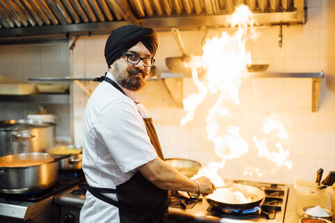 Indian chef flambing food in restaurant kitchen stock photo