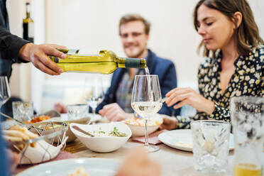 Freunde essen in einem indischen Restaurant, der Kellner schenkt Wein in Gläser ein - OCMF01046