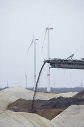 Germany, North Rhine-Westphalia, Inden, Conveyor belt of bucket-wheel excavator with wind turbines in background - HLF01214