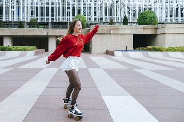 Happy young woman roller skating in the city - KIJF02903