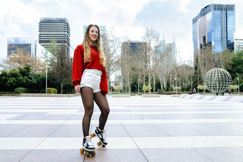 Portrait of happy young woman roller skating in the city stock photo