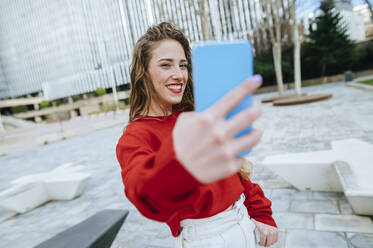 Lächelnde junge Frau macht ein Selfie in der Stadt - KIJF02905