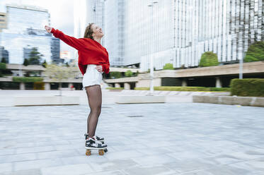 Happy young woman roller skating in the city - KIJF02906