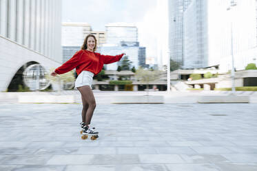Portrait of happy young woman roller skating in the city - KIJF02907