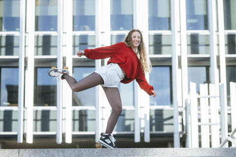 Portrait of happy young woman balancing on roller skates in the city stock photo