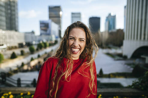 Portrait of happy young woman in the city sticking out her tongue - KIJF02921