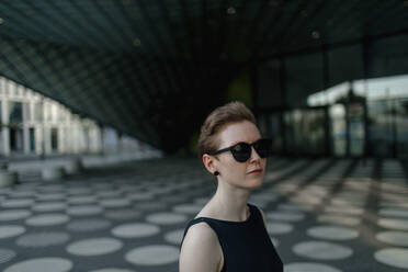 Elegante rothaarige Frau mit Sonnenbrille in der Stadt, Porträt - OGF00125