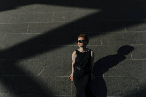 Rothaarige Frau mit Sonnenbrille, die das Sonnenlicht genießt, lizenzfreies Stockfoto