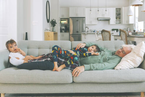 Vater und zwei Kinder entspannen sich auf der Couch - CMSF00083