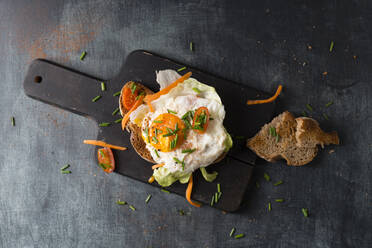 Fried egg with bread and vegetables lying on cutting board - MYF02258