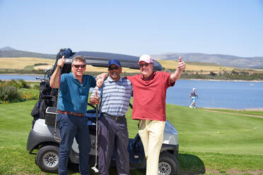 Porträt glücklicher reifer männlicher Golfspieler am Golfwagen auf einem sonnigen Platz - CAIF23853
