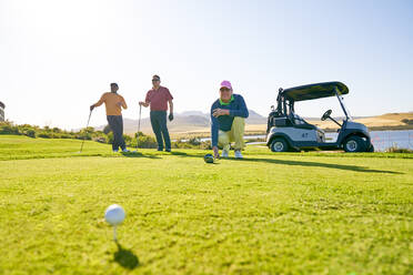 Männliche Golfer bereiten sich am sonnigen Abschlagplatz auf den Abschlag vor - CAIF23869