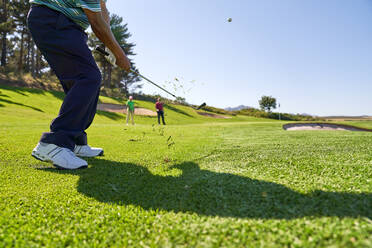 Männlicher Golfer bei einem Schlag auf dem sonnigen Golfplatz - CAIF23900