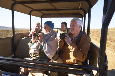 Glückliche Senioren mit Fernglas und Kamera auf Safari im Geländewagen - CAIF23909