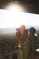 Älteres Paar mit Kamera auf sonnigem Safaribalkon - CAIF23935