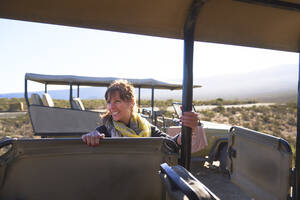 Glückliche reife Frau steigt in Safari-Geländewagen ein - CAIF23951