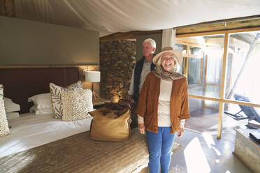 Porträt eines glücklichen älteren Paares bei der Ankunft im Hotelzimmer einer Safari-Lodge - CAIF23966