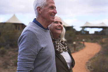 Glückliches Seniorenpaar auf dem Fußweg vor der Safari-Lodge - CAIF23974