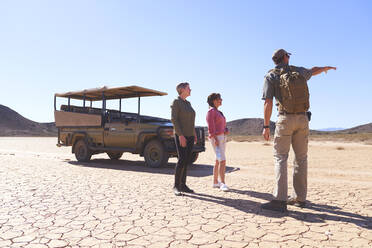 Safari-Reiseleiter im Gespräch mit Touristen in der sonnigen trockenen Wüste Südafrikas - CAIF23980