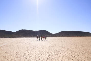 Safari-Tour-Gruppe, die entlang der sonnigen, rissigen Erde wandert Südafrika - CAIF23983