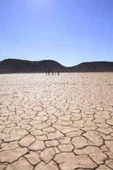 Safari-Tour-Gruppe, die entlang der sonnigen, rissigen Erde wandert Südafrika - CAIF23985