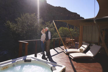 Senior couple on sunny luxury safari lodge hotel balcony - CAIF23995