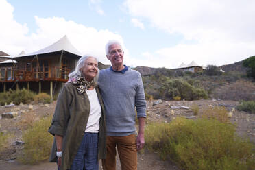 Glückliches älteres Paar vor der Hütte einer Safari-Lodge - CAIF24006