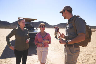 Safari-Reiseleiter im Gespräch mit Frauen in der sonnigen Wüste Südafrikas - CAIF24008