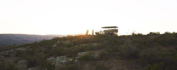 Safari-Gruppe und Geländewagen auf einem Hügel bei Sonnenaufgang in Südafrika - CAIF24016