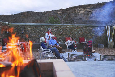 Ältere Freunde entspannen sich bei Rotwein auf der Hotelterrasse mit Feuerstelle - CAIF24020