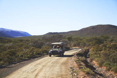 Safari-Geländewagen auf sonniger, unbefestigter Straße in Südafrika - CAIF24038