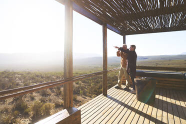 Älteres Paar mit Blick auf die sonnige Aussicht vom Balkon einer Safari-Lodge - CAIF24051