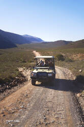 Safari im Geländewagen auf einer sonnigen, abgelegenen Straße in Südafrika - CAIF24059