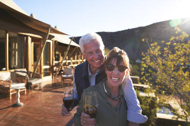 Porträt glückliches älteres Paar trinkt Eistee auf sonnigem Hotelbalkon - CAIF24082
