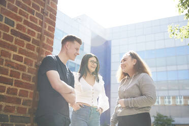 College students talking outside sunny building - CAIF24091