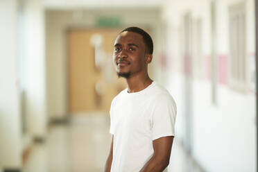 Portrait confident young male college student in corridor - CAIF24118