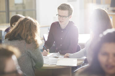 Junge Studenten studieren gemeinsam in einem sonnigen Klassenzimmer - CAIF24159