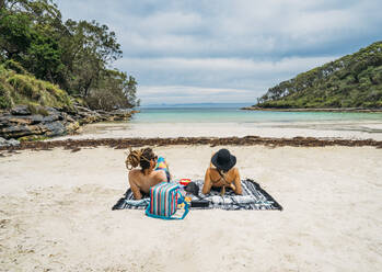 Paar beim Sonnenbaden an einem abgelegenen tropischen Strand in der Jervis Bay, Australien - CAIF24191